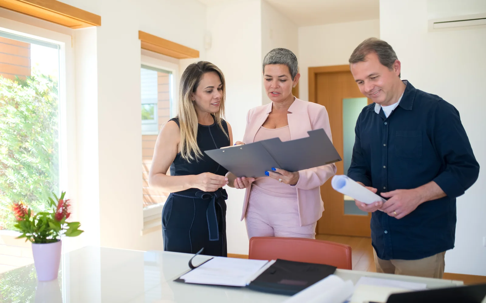 Eigentümer und Immobilienfachfrau besprechen Unterlagen in einem hellen Raum
